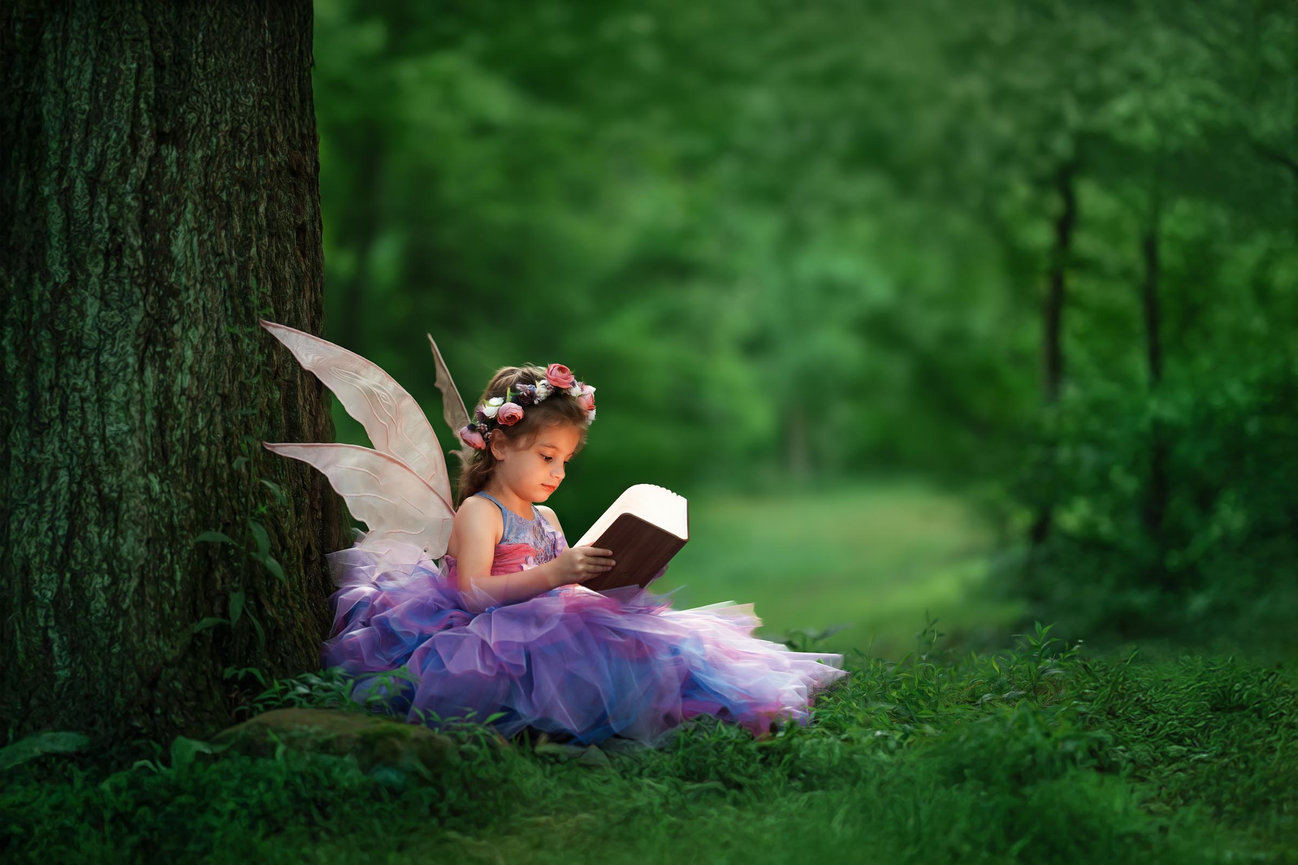 a little fairy in a purple gown sitting under a tree reading  during a Fine Art outdoor session with Marsha Lynn Photography