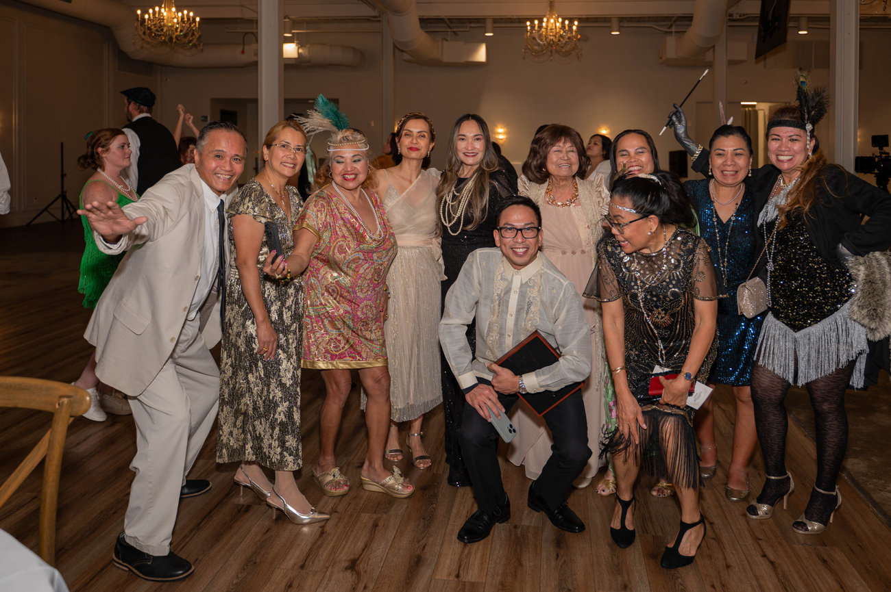 A group of people in festive attire posing together in a ballroom setting at The Casey captured by Jo Hayes Images Charlotte Event Photography