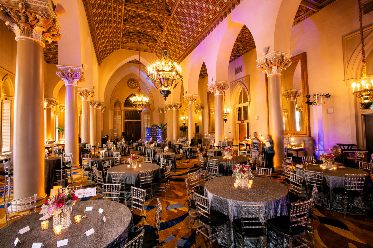 Elegant banquet hall with chandeliers, arched ceilings, and round dining tables set for an event