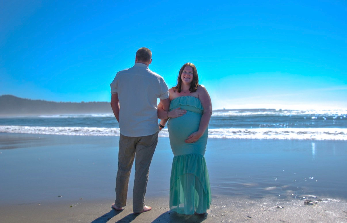Pregnant couple standing together on the beach