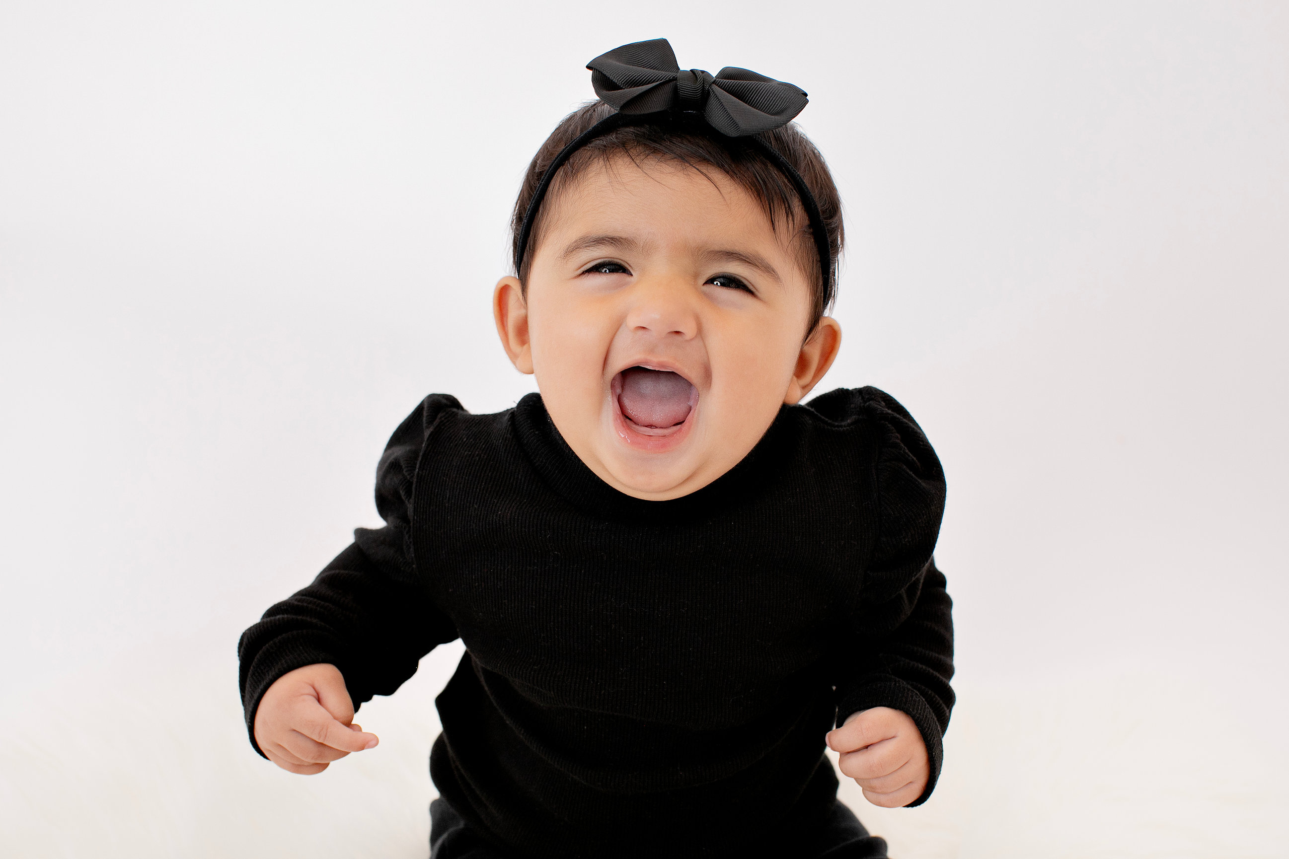 Baby laughing in a black outfit and matching bow