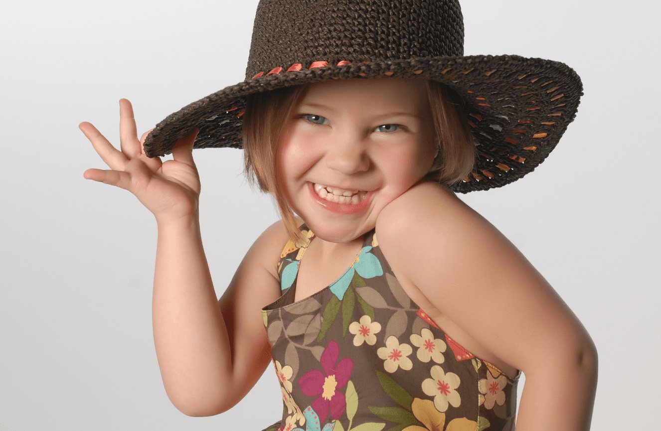 A childhood portrait of Avery tipping her brown straw hat during her photo session at Kliks Photography in Cedar Rapids, Iowa.