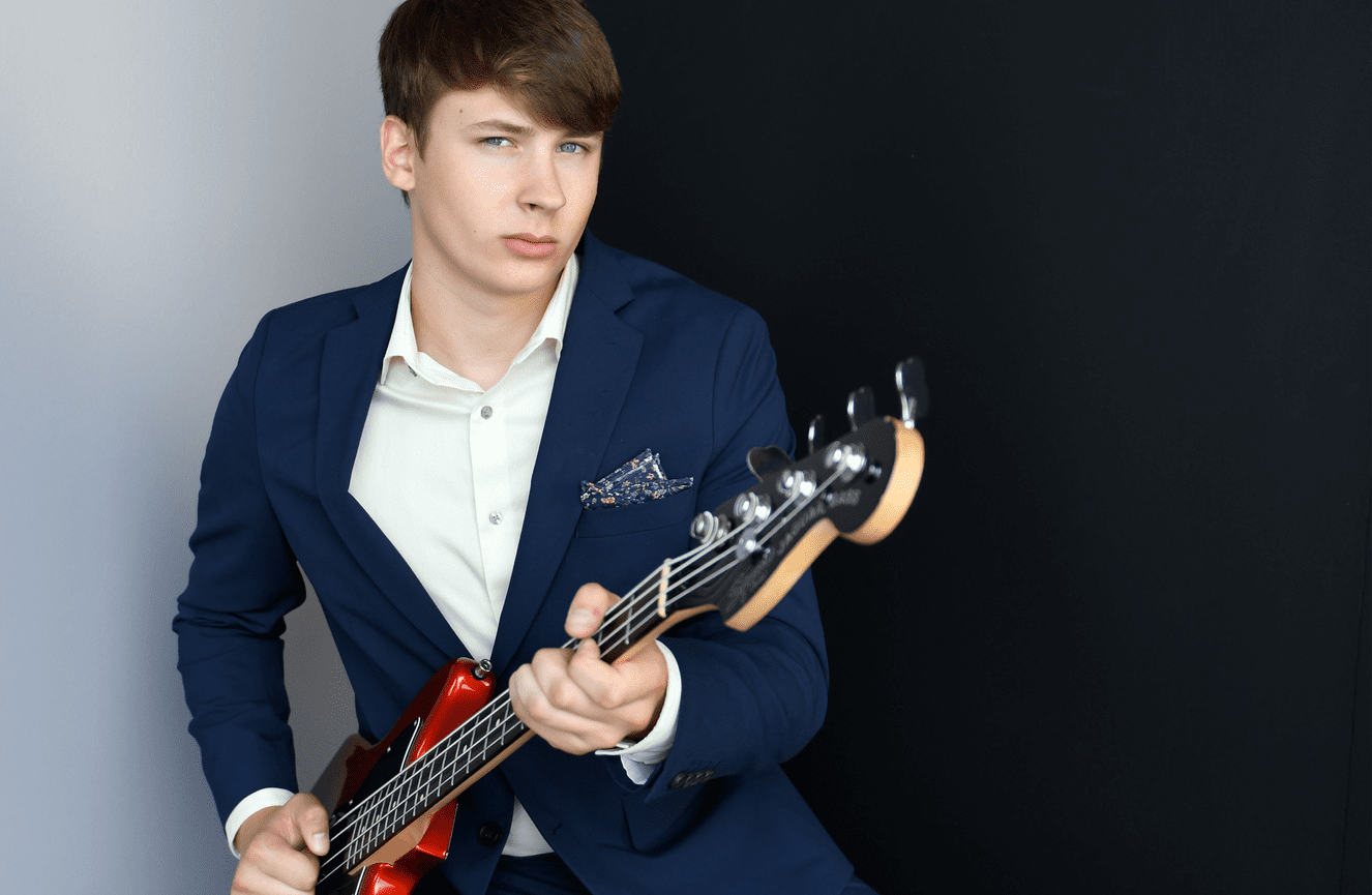 Leo is playing his electric guitar during his high school senior photo session at Kliks Photography.