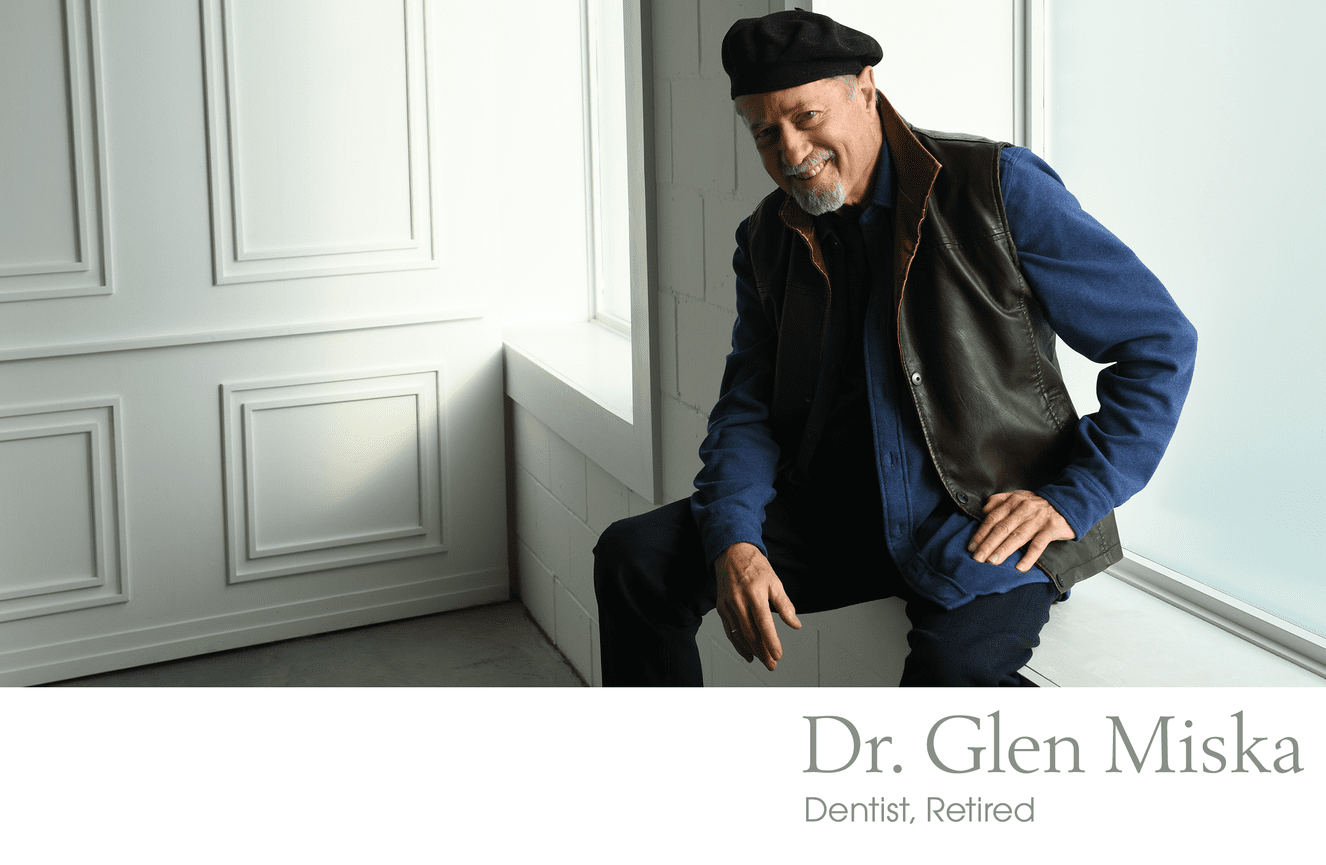 A promotional portrait of Dr. Miska wearing a black beret sitting in the window sill at Kliks Photography in Cedar Rapids, Iowa.