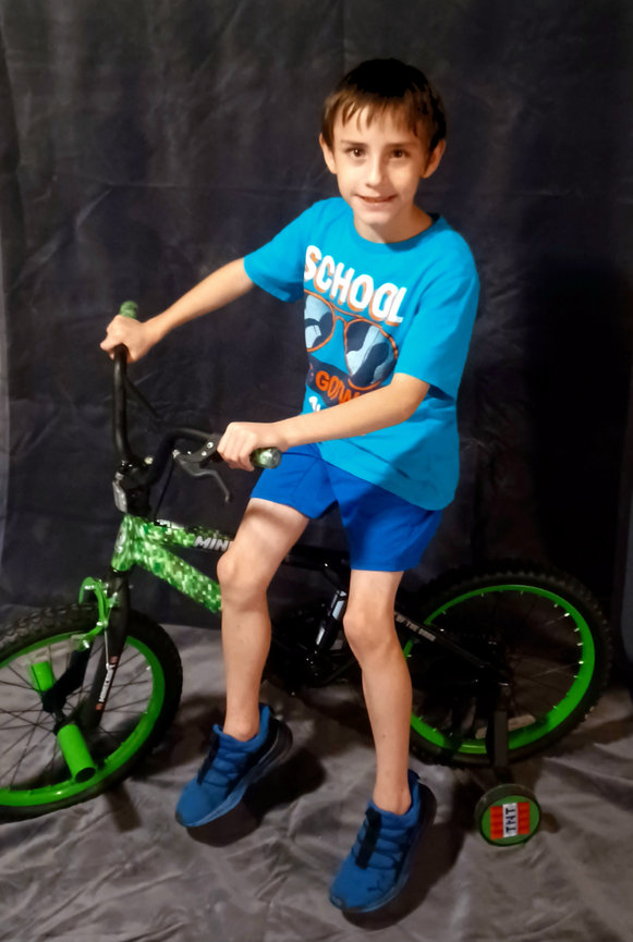 Boy in blue shirt riding a bicycle indoors