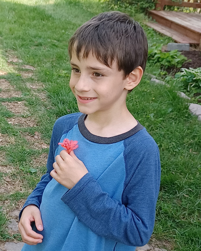 Boy holding a small flower in a garden
