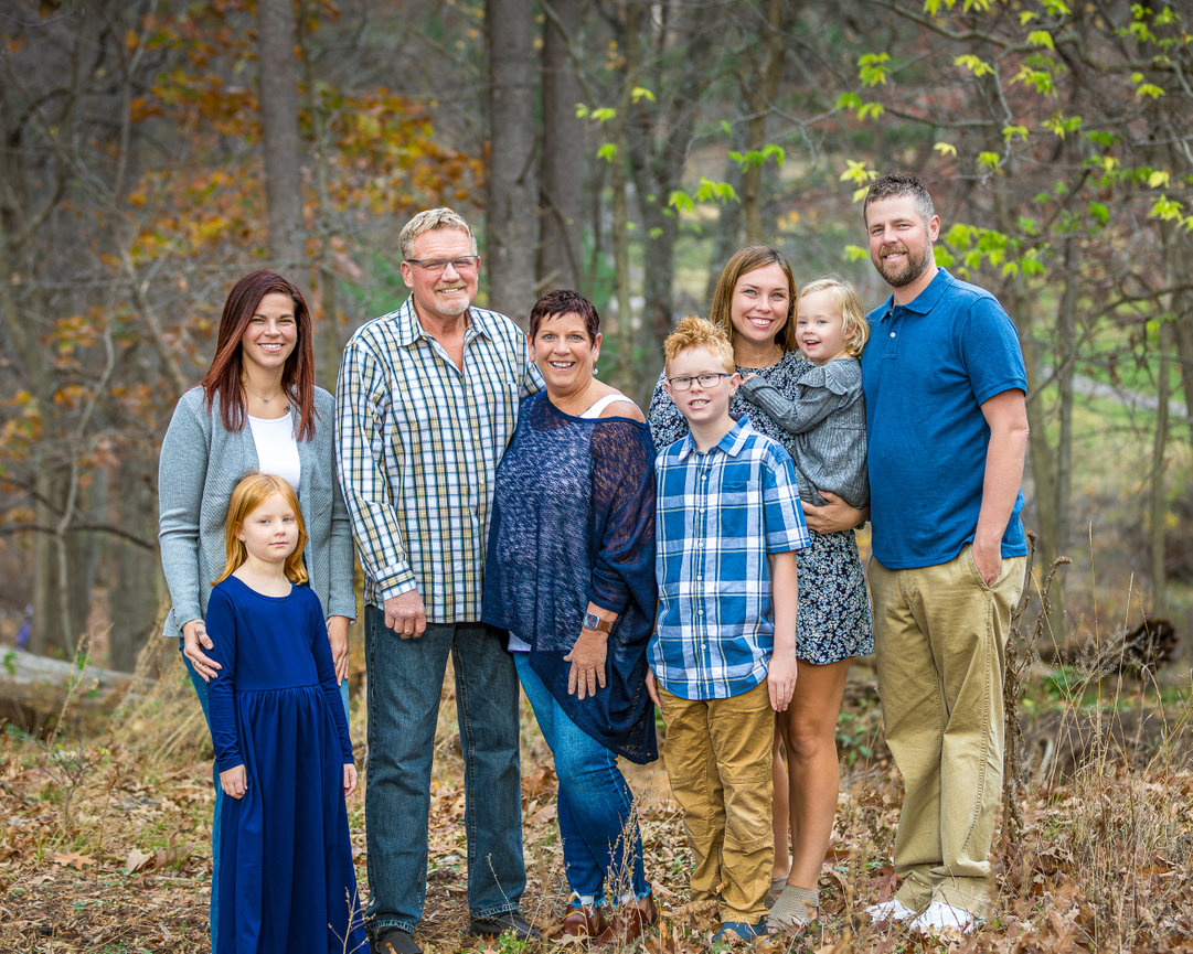 Large multi-generational family posing in a wooded area