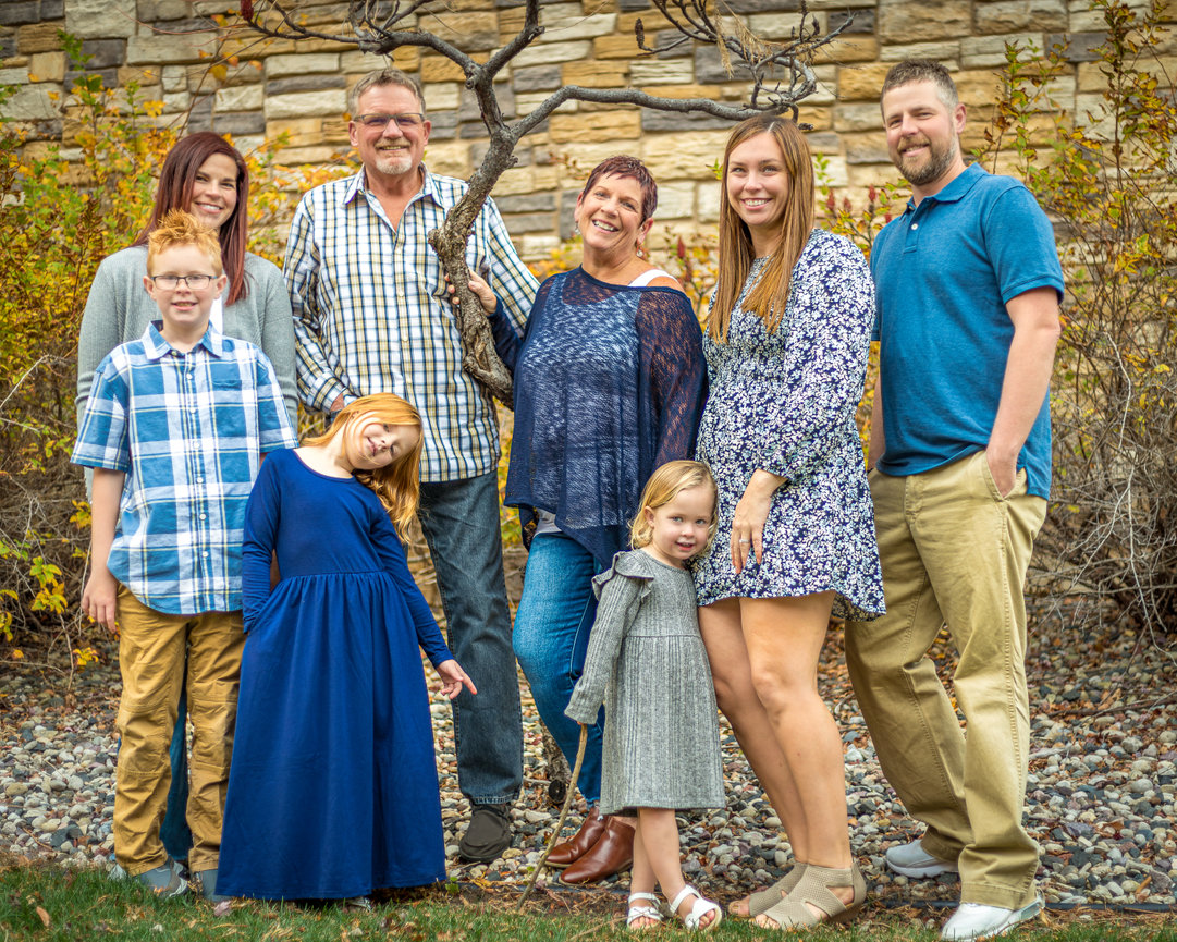 Family of seven posing by a stone wall in an outdoor setting