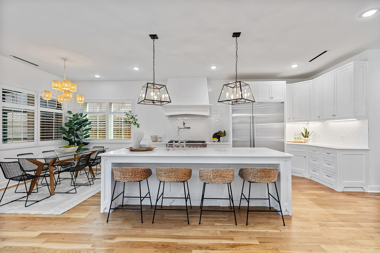 Bright modern white kitchen with island, pendant lights, and breakfast nook