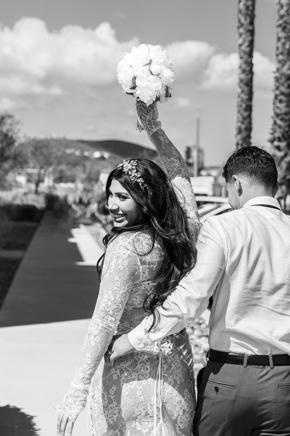 Black and white photo of couple celebrating with raised bouquet