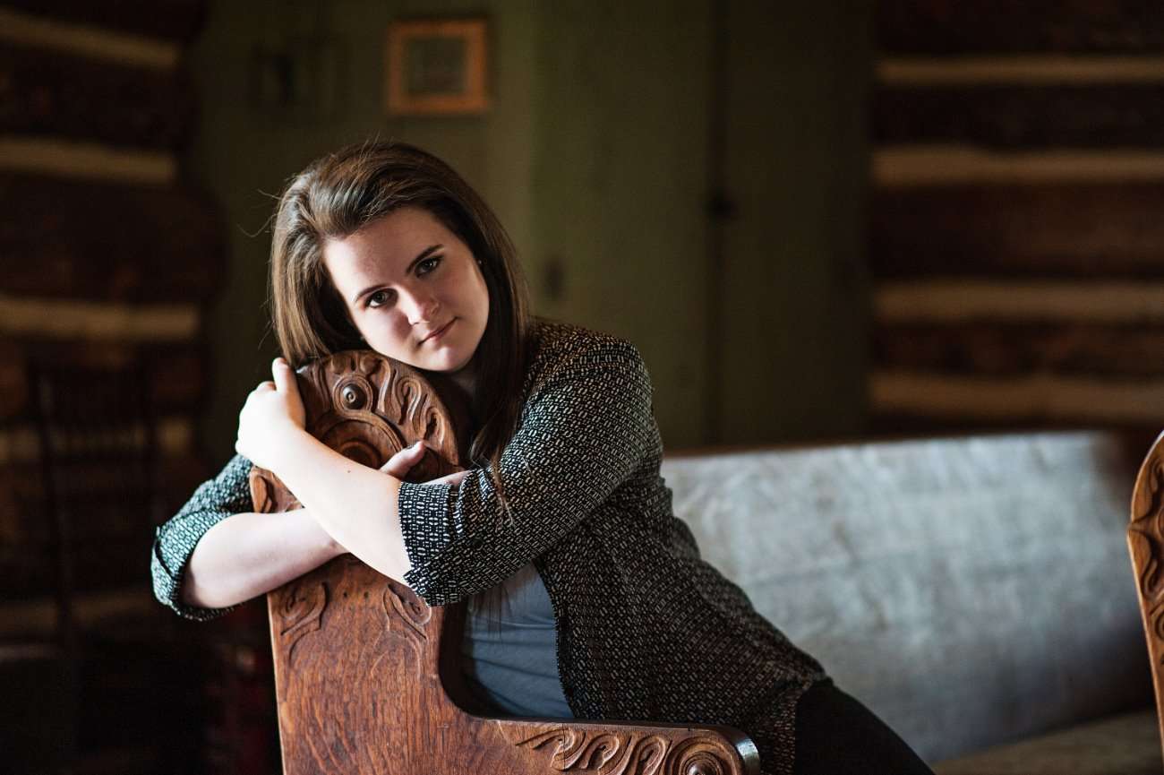 senior girl sitting on church pew inside Hope Wilderness Chapel at Dogwood Canyon