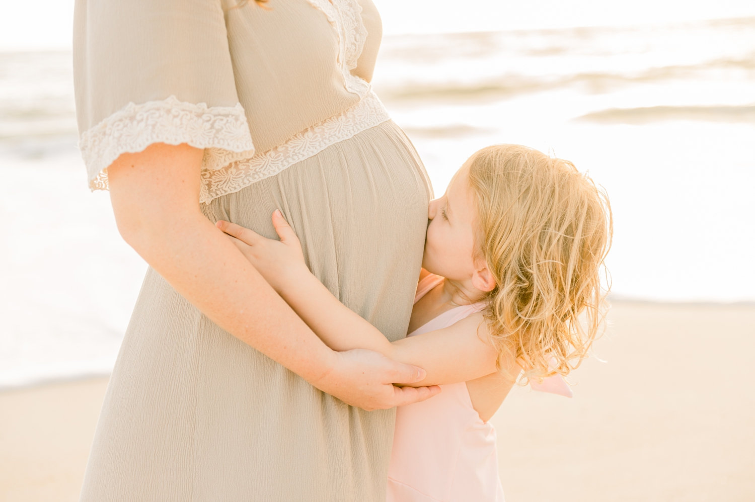 little girl kissing her mother's baby belly, St. Augustine family maternity portraits